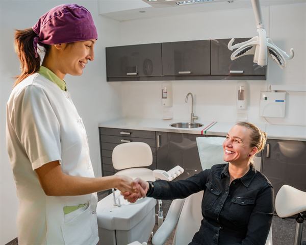 Tandarts begroet patiënt voor algemene controle bij Dentique Clinics